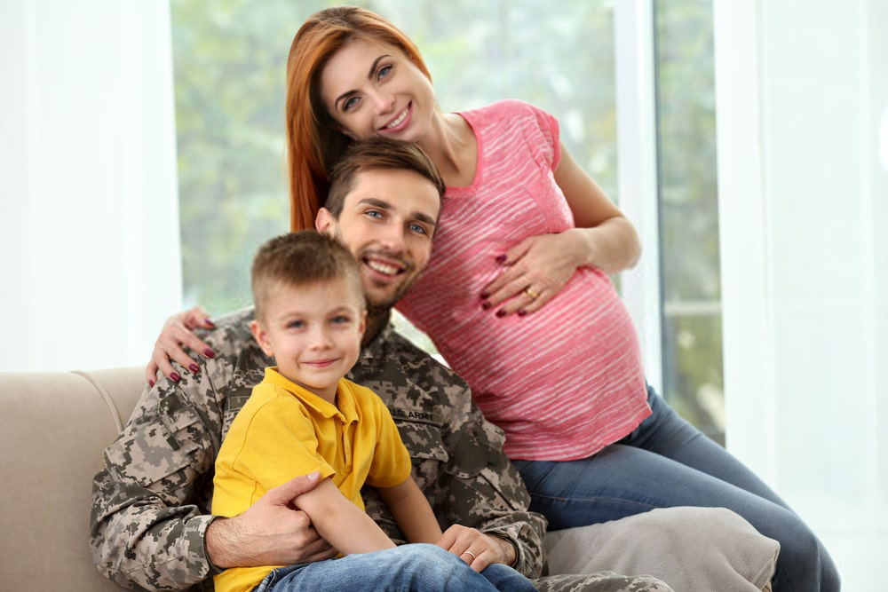 militar do concurso esa 2021 com seu filho no colo e sua mulher grávida ao lado